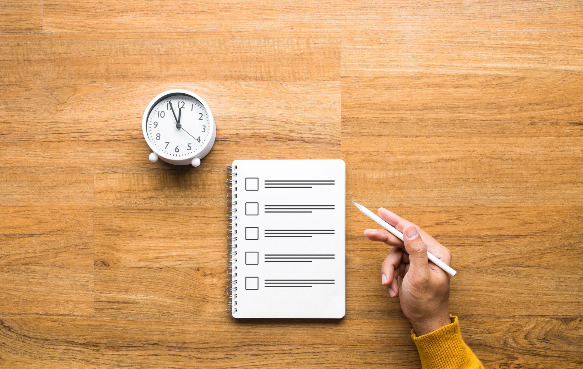 Exam and time management concepts with male hand holding pencil and paper sheet on table